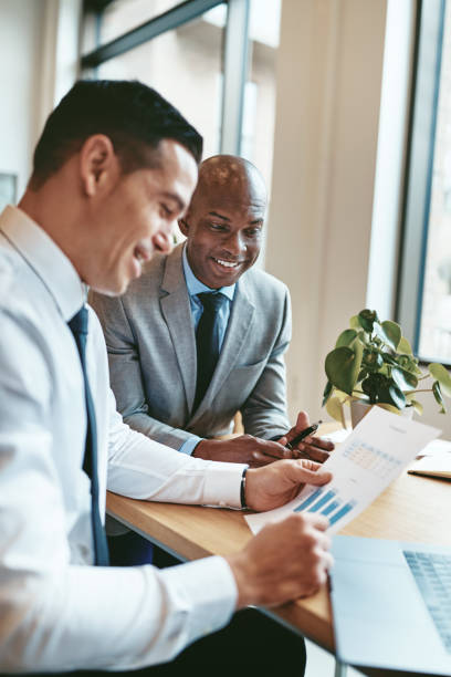 istock Two diverse businessmen smiling while reading paperwork in an office 1185684085