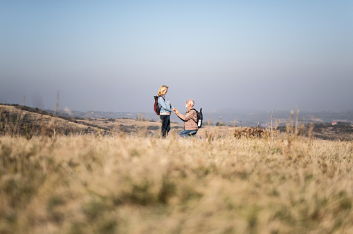 Senior man proposing to his woman in nature.