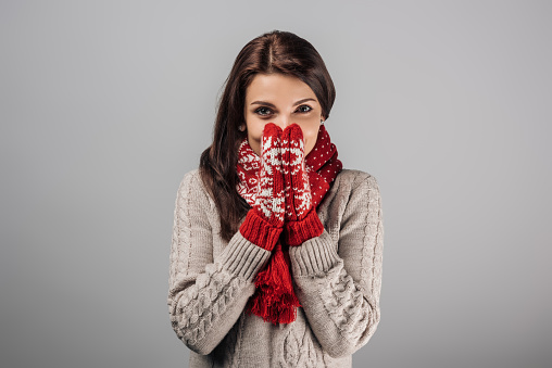 woman in red gloves and scarf covering face isolated on grey