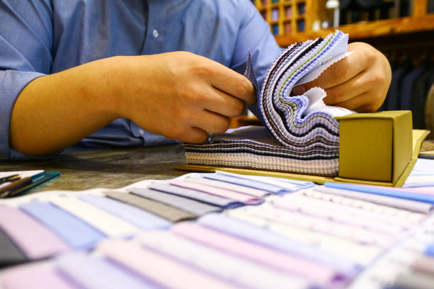 istock tailor choosing a fabric in swatch for his customer 1185687150