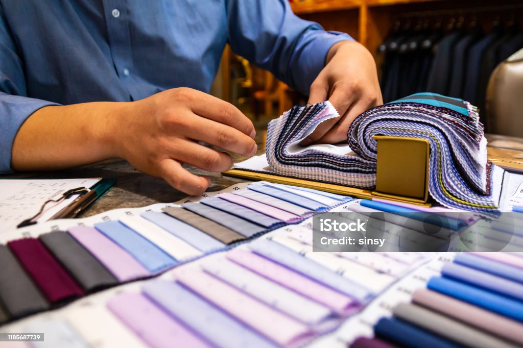 tailor choosing a fabric in swatch for his customer tailor choosing a fabric in swatch for his customer in tailor shop Customized Stock Photo