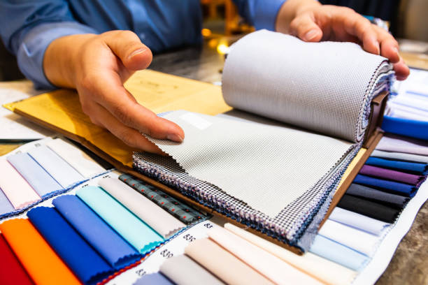 istock tailor choosing a fabric in swatch for his customer 1185691414