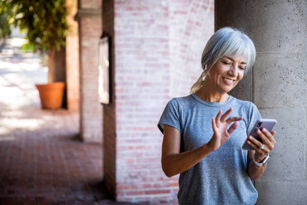 starsza kobieta używająca smartfona podczas treningu - mature adult women care listening zdjęcia i obrazy z banku zdjęć