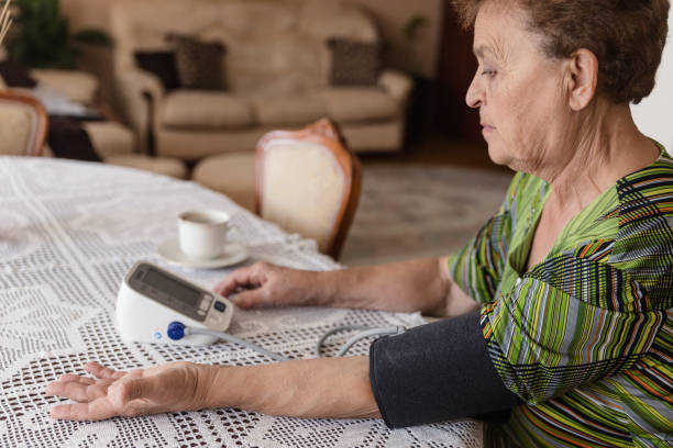 senior vuxen kvinna mäta blodtryck hemma - blodtryck orolig bildbanksfoton och bilder