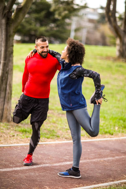 istock Young athletic couple stretching while embracing each other on an all-weather running track in a city park 1185705352
