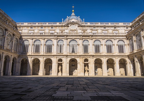 This image captures shows the exterior of The Royal Palace of Madrid on a sunny day with a beautiful blue sky in the background.