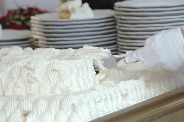 Waiter cutting the white wedding whipped cream cake
