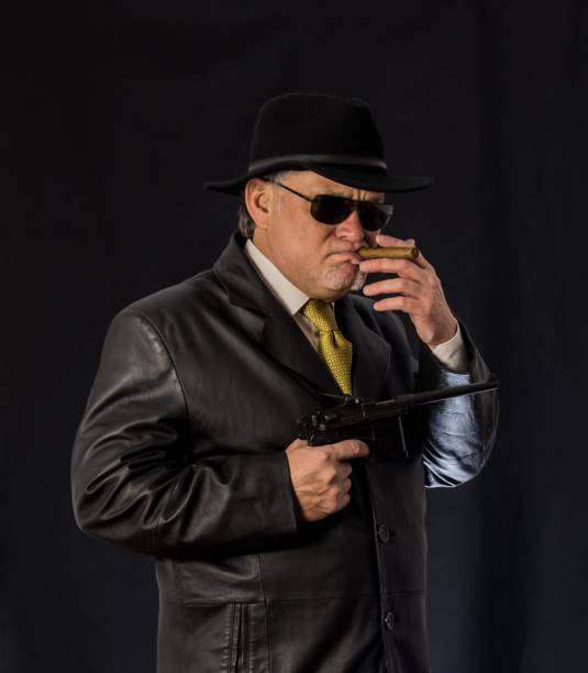 istock Ganster with a cigar and Mauser system pistol. Mafiosi in black gla 1185710836