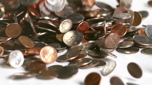 US coins falling onto a white surface in slow motion
