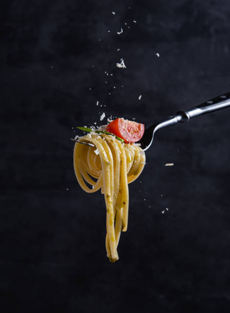 トマトとペストをフォークに乗したタリアテッレ。イタリア料理。暗い背景 - spaghetti tomato preparing food italian cuisine ストックフォトと画像