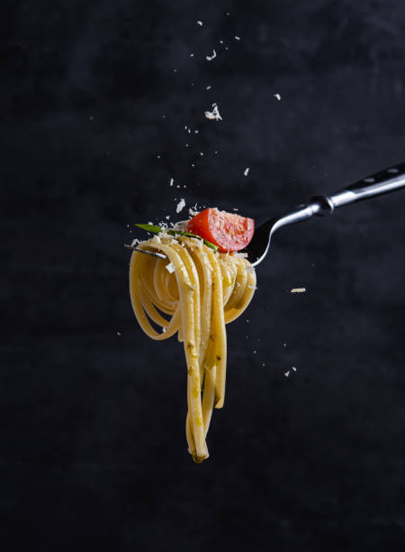 토마토와 페스토를 포크에 얹은 타글리아텔. 이탈리아 음식. 어두운 배경 - italian cuisine food preparing food cheese 뉴스 사진 이미지