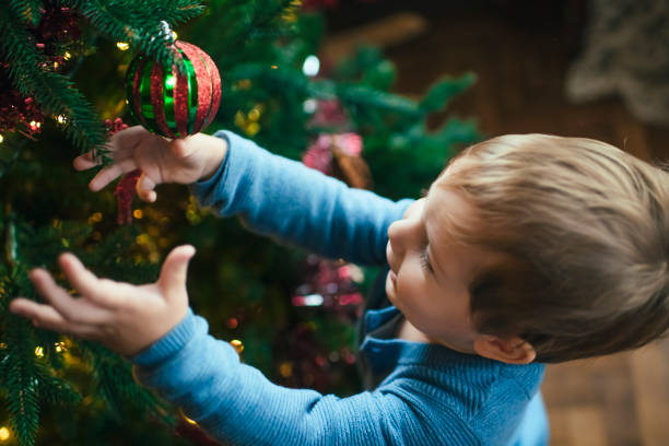 istock Little boy indoors decorating Christmas tree 1185719083