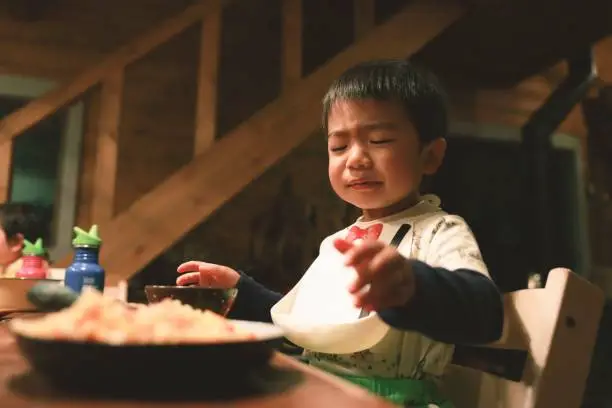 Asian little boy is trying to eat his hates eating
