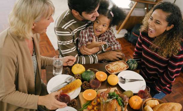 happy family celebrando la cena de acción de gracias en casa. concepto de la tradición de celebración - thanksgiving cheerful happiness gratitude fotografías e imágenes de stock