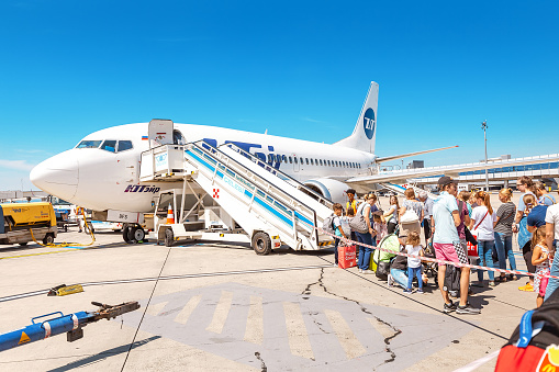 09 August 2019, Vienna, Austria: People stay in line boarding to an airplane of UTair airlines