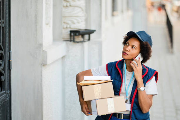 istock Black female courier talking on the phone while delivering packages. 1185724909