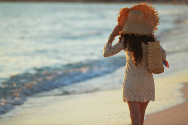istock elegant middle age woman on seashore at sunset walking 1185725873