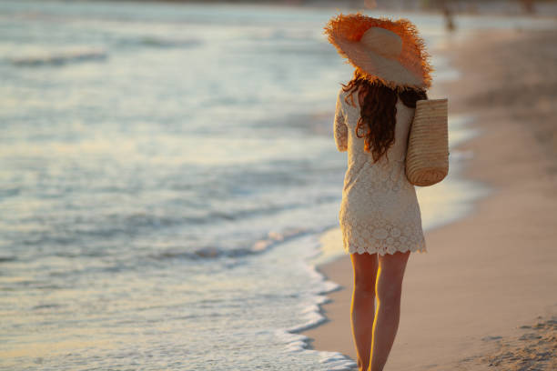 istock stylish woman on seashore at sunset walking 1185725875