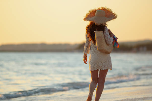 istock elegant middle age woman on beach at sunset walking 1185725941
