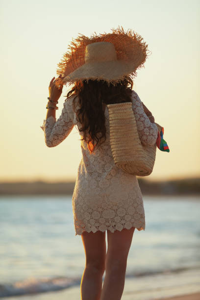 istock modern middle age woman on seashore at sunset walking 1185725942