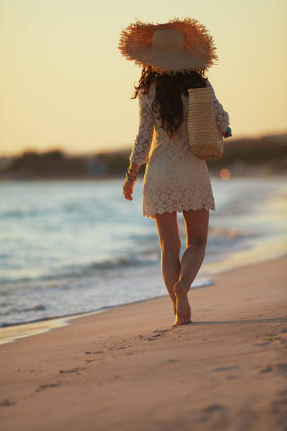 istock modern middle age woman on seashore at sunset walking 1185725943