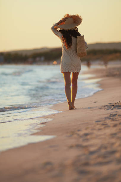 istock 40 year old woman on beach at sunset walking 1185725969