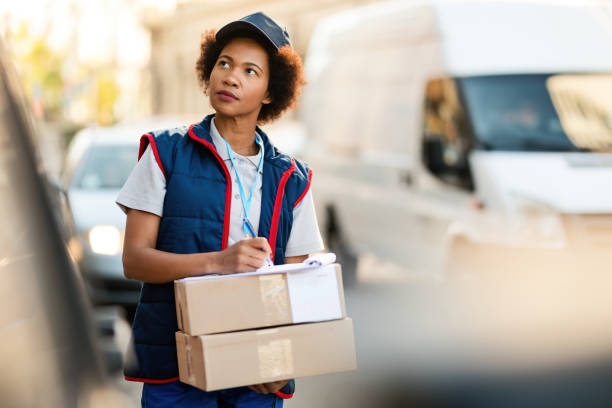 istock Black female courier writing address while making delivery in the city. 1185726015