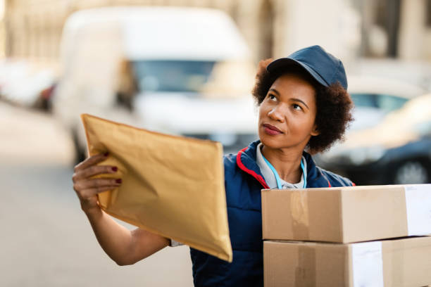 istock African American courier with packages checking if she is on right address. 1185726262