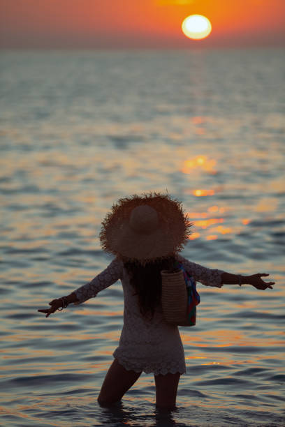 istock elegant woman with open arms rejoicing while standing in ocean 1185726296