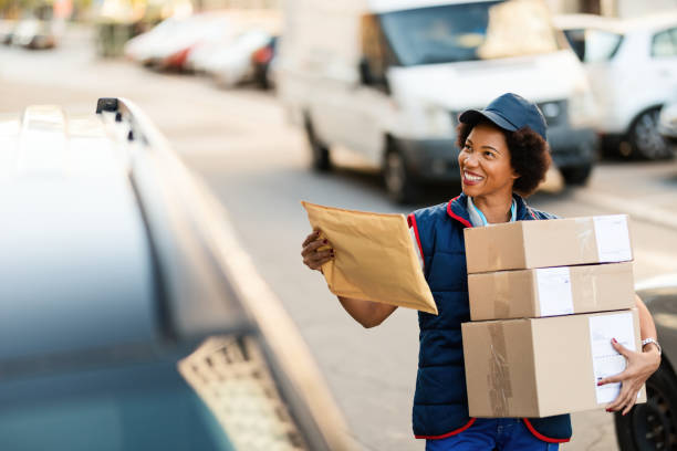 istock Happy black postal worker delivering packages in the city. 1185726313