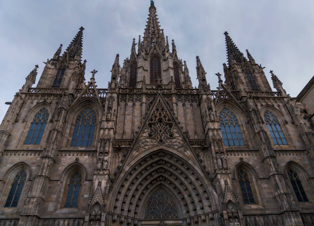 This image capture shows the exterior of the majestic Cathedral of Barcelona with ominous gray cloudy behind.