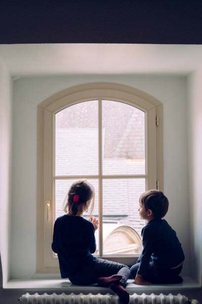 istock Small siblings waiting for Santa Claus looking through the window. 1185730031
