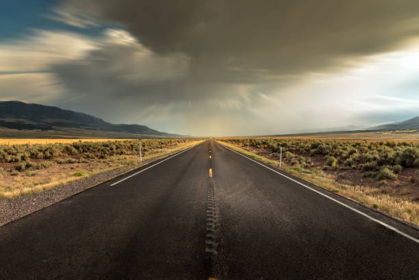 istock Long straight road in Utah with dramatic clouds and rain rolling in 1185730493
