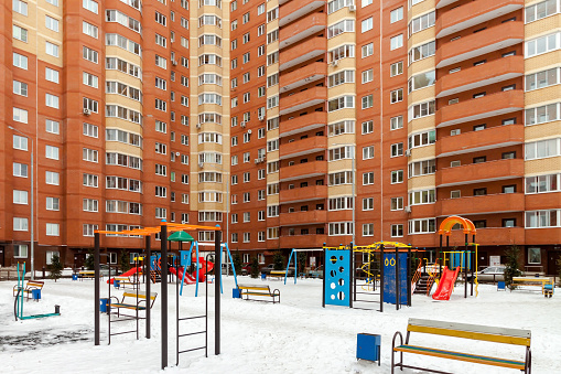 Playground for children and house building exterior mixed-use urban multi-family residential district area development winter time