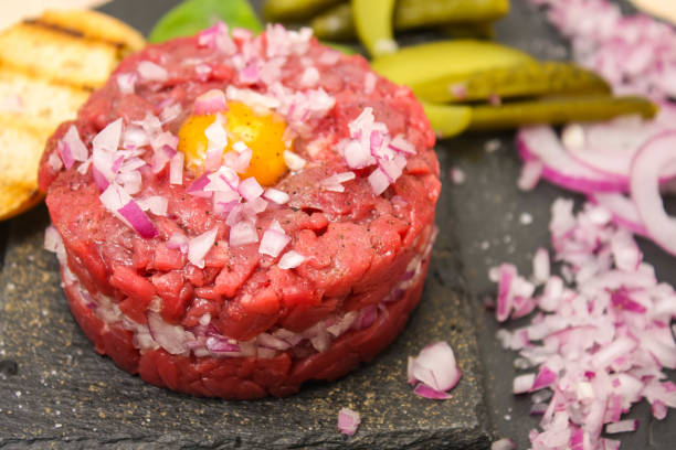 istock beef fillet tartare with egg, on a black basalt Board. 1185734506