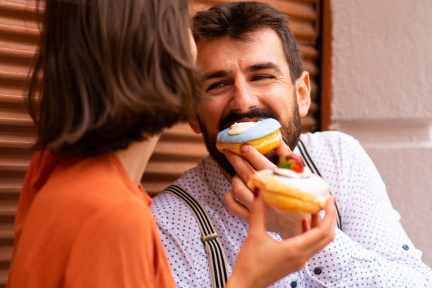 istock Couple eating doughnuts on street. 1185741455