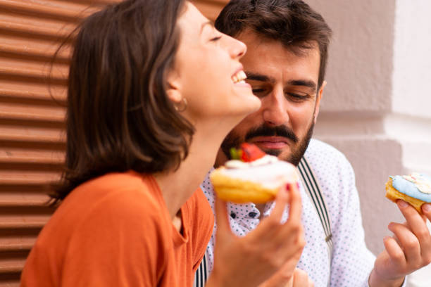 istock Couple eating doughnuts on street. 1185741686