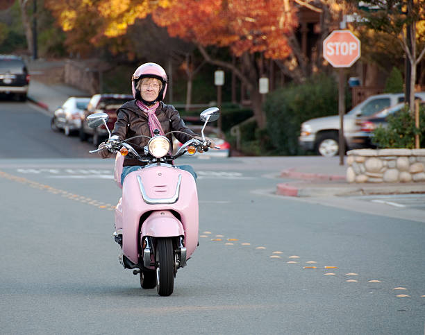 Pink moped with a shopping basket on drivers seat. Pink background.