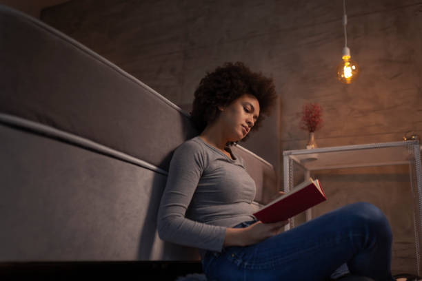 istock Woman sitting next to bed and reading a book 1185749590