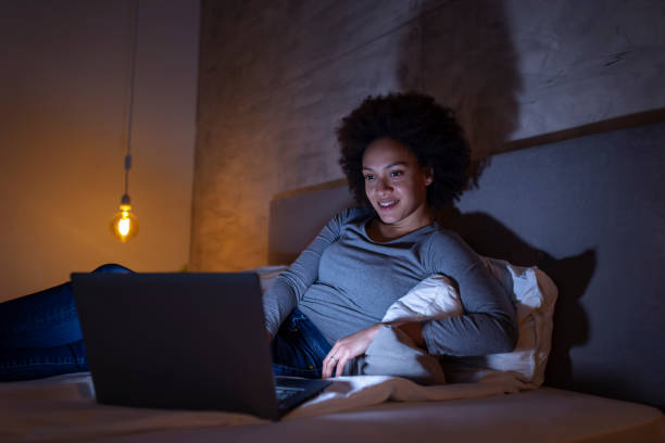 istock Woman lying in bed and having a video call on laptop computer 1185749814