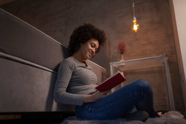 istock Woman reading a book at home 1185749844