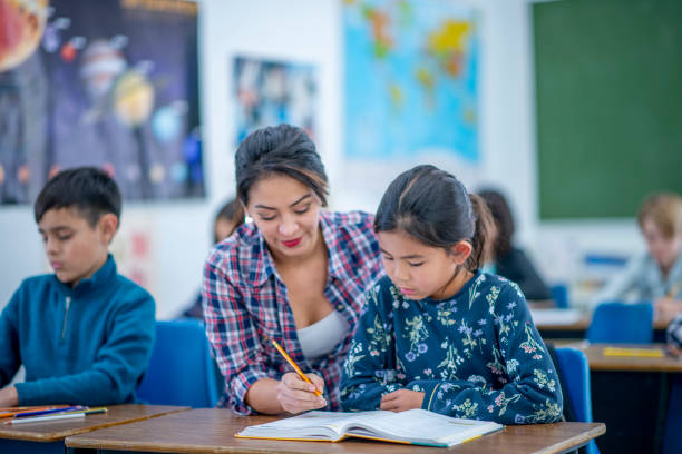 istock Female Teacher Helping an Elementary Student In Class stock photo 1185750586