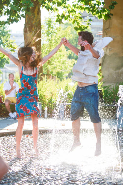 Three friends jumping into a fountain.