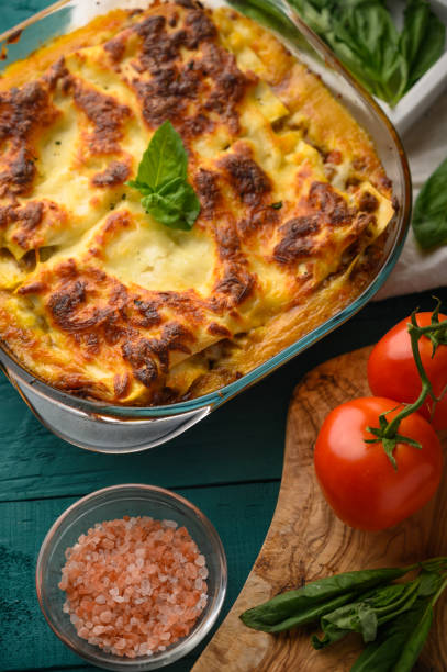 istock Ready Italian lasagna, on a green wooden background with basil, tomatoes. Culinary background, book of Italian recipes, delicious food. Vertical frame 1185754870