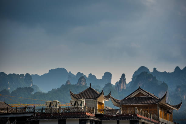 Rooftops of traditional chinese buildings with the stunningly beautiful rocky karst mountain formations behind as seen from the centre of Wulingyuan town, Hunan Province, China