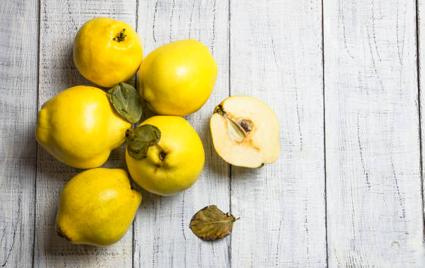 Fresh ripe organic half and whole quinces on rustic background. Healthy yellow fruit quince, Cydonia oblonga stock photo
