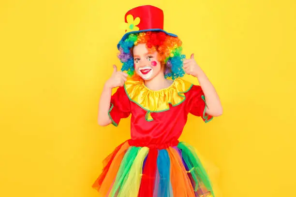 Photo of Little girl in clown costume and hat showing like sign
