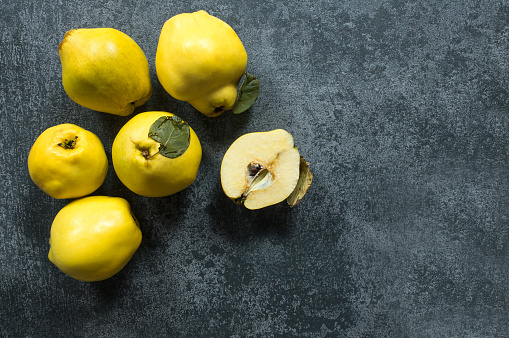 Fresh ripe organic half and whole quinces on rustic background. Healthy yellow fruit quince, Cydonia oblonga