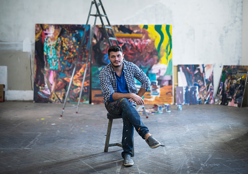 Young artist working on a big painting in his atelier