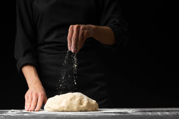 istock The chef cooks the dough for pasta, pizza, bread and rolls, on a dark background with space. 1185768163